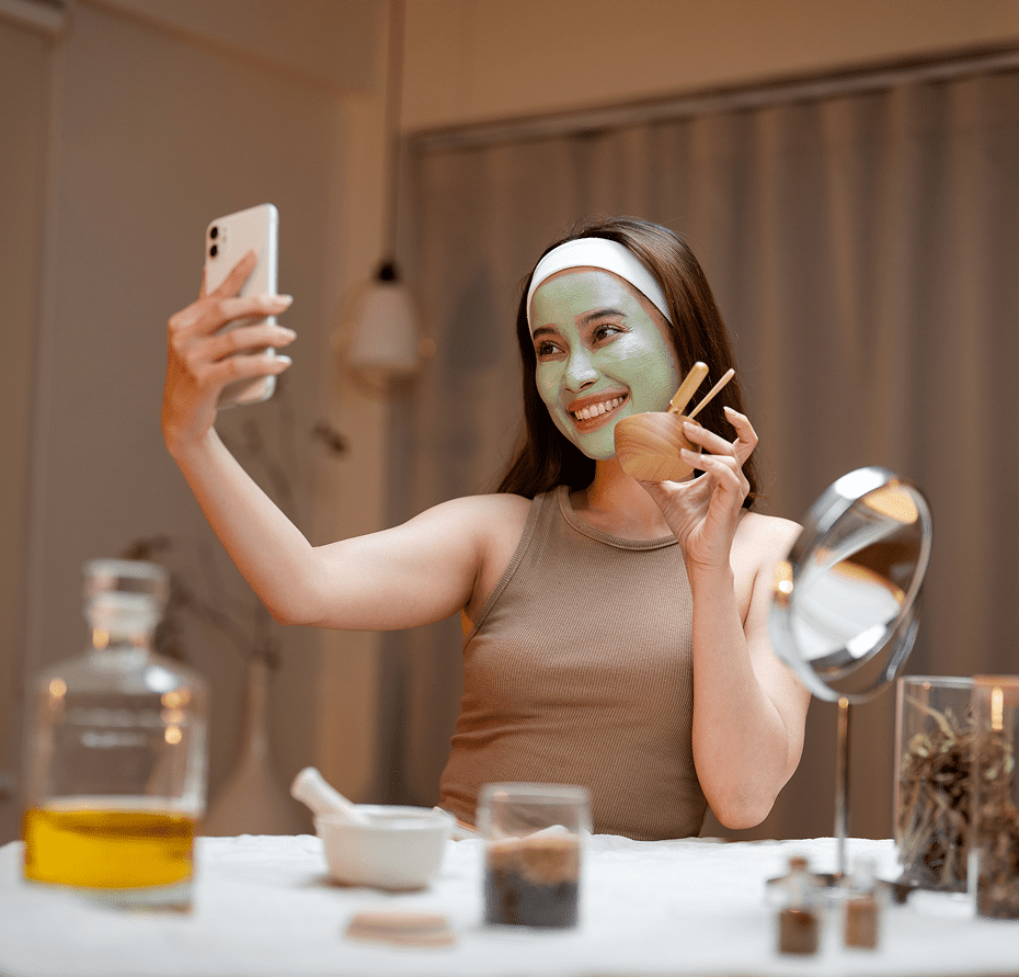 Woman taking selfie with facial mask on.