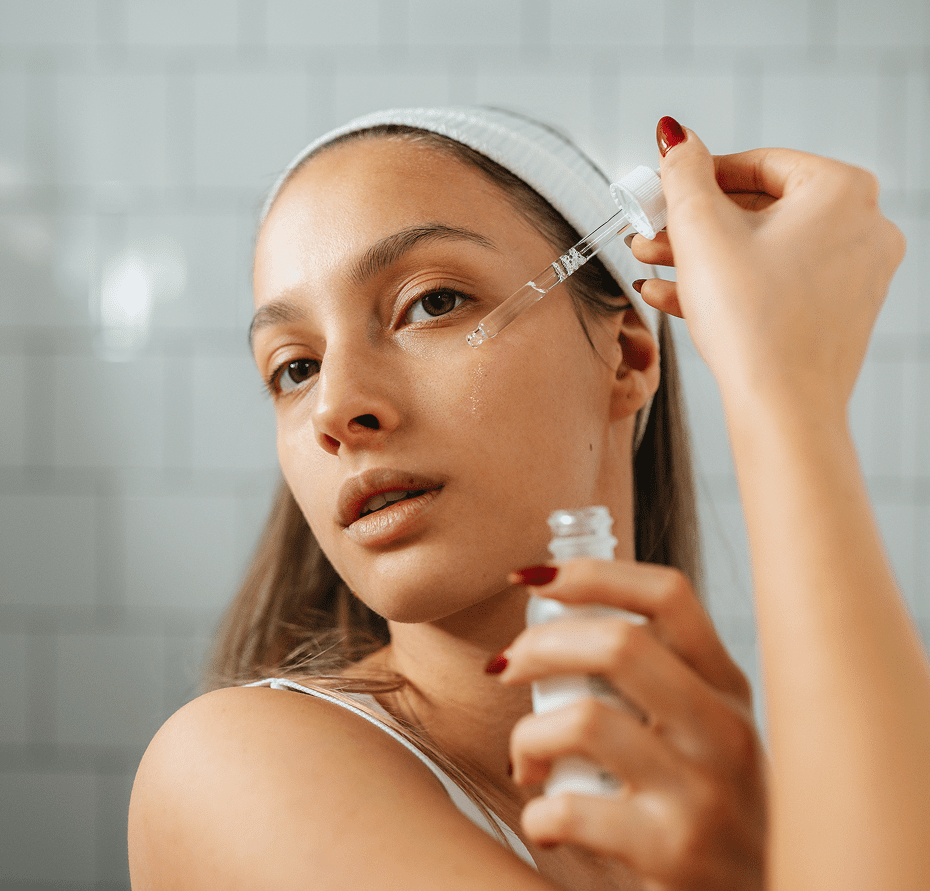 Woman applying skincare serum with dropper.